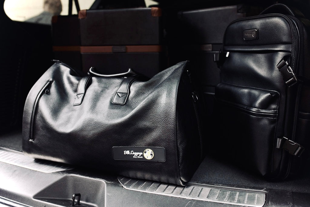 BLK Weekend garment bag and Overnight backpack packed in a car trunk.